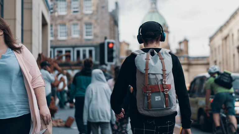 Symbolbild für Audiowalk - Person mit Kopfhörern unterwegs auf der Straße