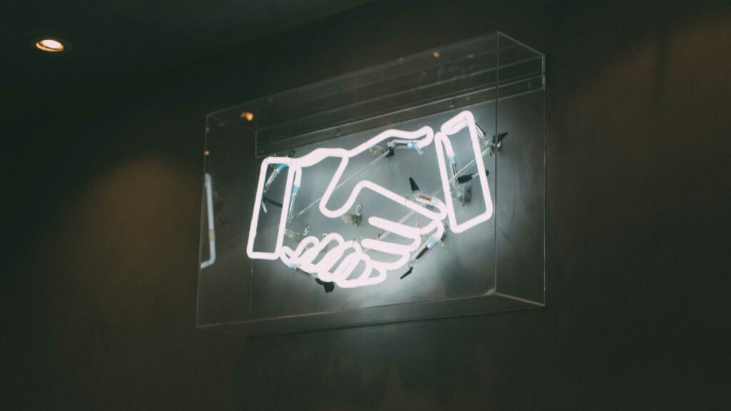 Ein Kunstobjekt, das einen Handschlag mit Neonleuchten darstellt. 