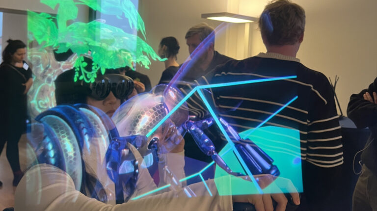 Teilnehmende unsere Augmented Reality-Workshops. Auf dem Foto, das durch eine AR-Brille aufgenommen wurde, sind virtuelle Objekte im Raum sichtbar.