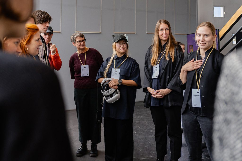 Annette Kleffel und drei Referentinnen von SOMA ART Berlin, von links nach rechts - Nabi Nara, Dagmar Schürrer und Marlene Bart, stehen in der Galerie. Nabi Nara trägt eine VR-Brille in der Hand. Die Stimmung ist konzentriert und interessiert.