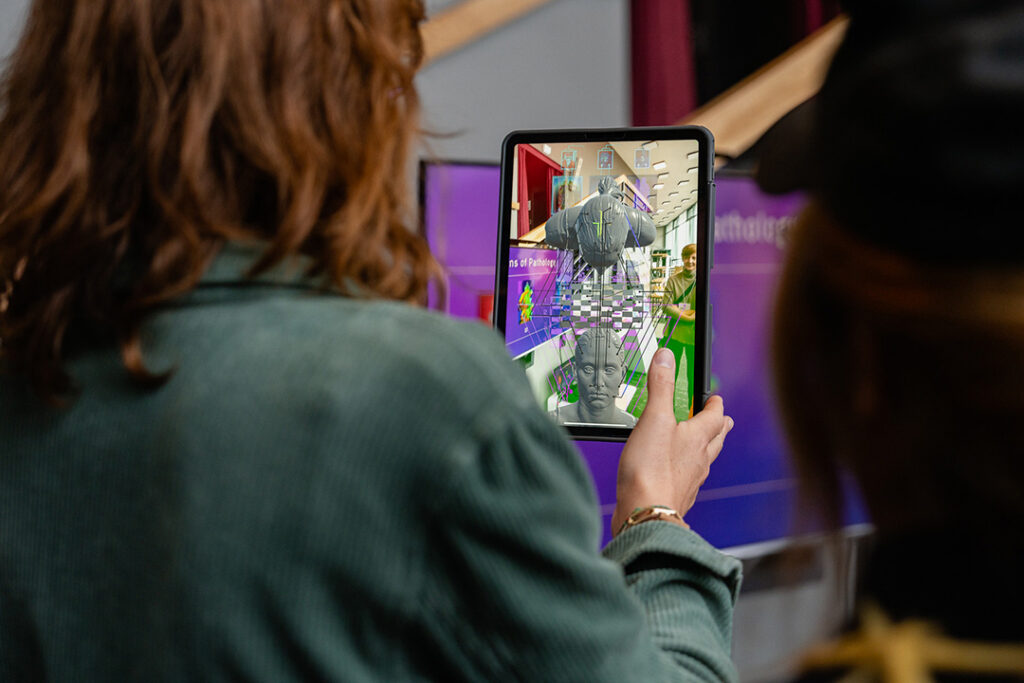Nahaufnahme einer Person, die ein Tablet hält und darauf eine AR-Anwendung erkundet.