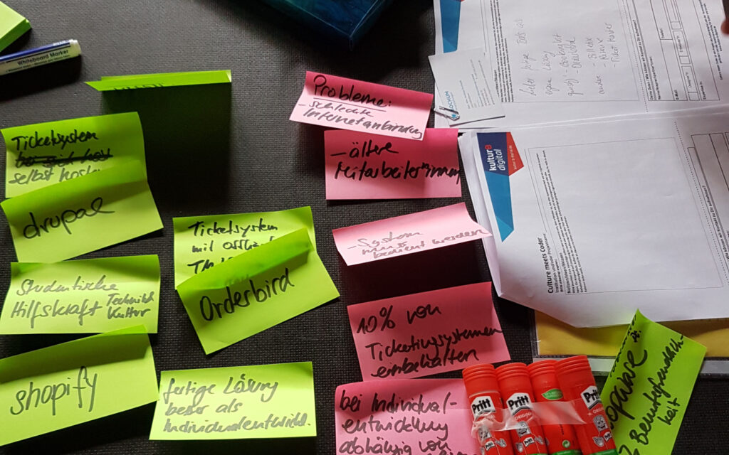 Bunte Klebezettel mit Notizen neben einem Steckbrief des Projekts Culture meets Coder.