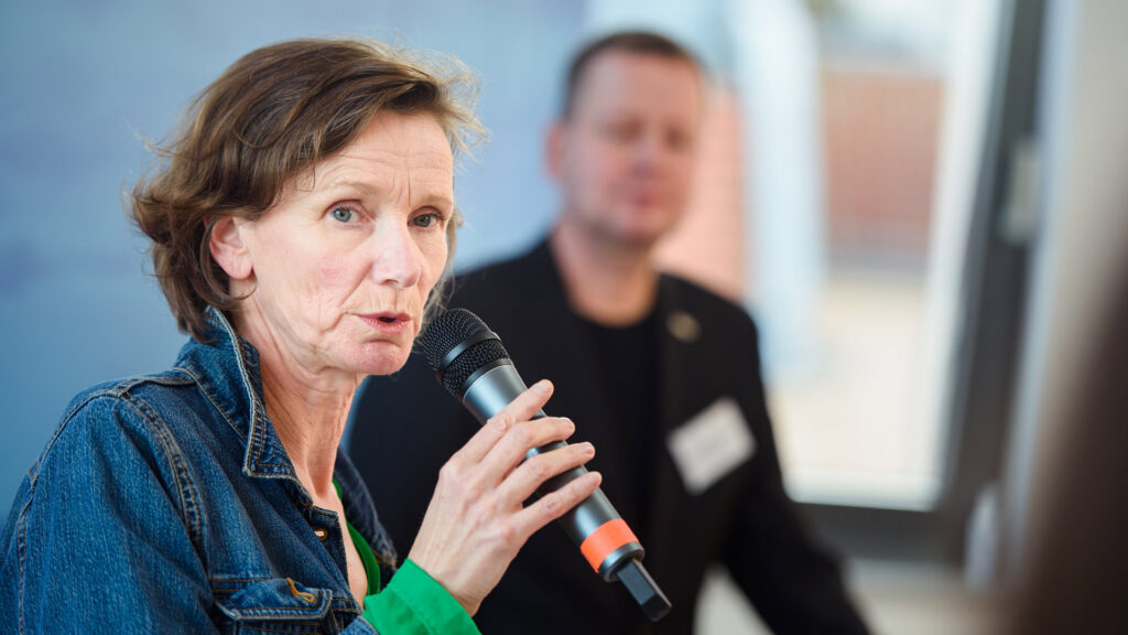 Esther Cleven (Bauhaus Archiv) spricht auf der kulturBdigital-Konferenz 2020 in ein Mikro, im Hintergrund: Kultursenator Klaus Lederer.