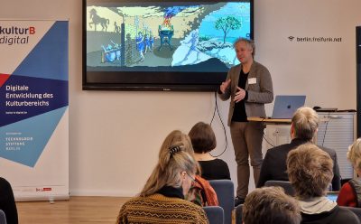 Oliver Proske beim Werkstattgespräch zu Augmented Reality. Auf dem Bildschirm hinter ihm: Eine Illustration von Platons Höhlengleichnis.