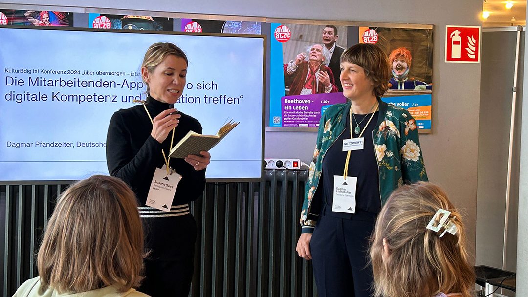 Zwei Moderatorinnen, Dagmar Pfandzelter und Susana Saez, stehen vor einer Präsentation zur Mitarbeitenden-App.