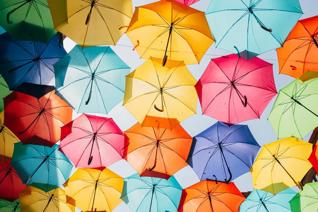 Bunte, nebeneinander aufgespannte Regenschirme schützen vor Sonnenstrahlen