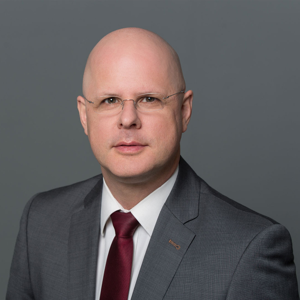 Porträt von Dr. Alexander Steinhilber vor blauem Hintergrund