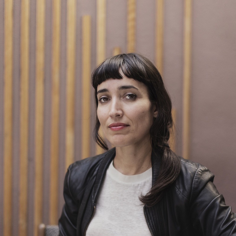 Porträt von Fernanda Parente vor einer Holzlamellen-Wand, in schwarzer Lederjacke.